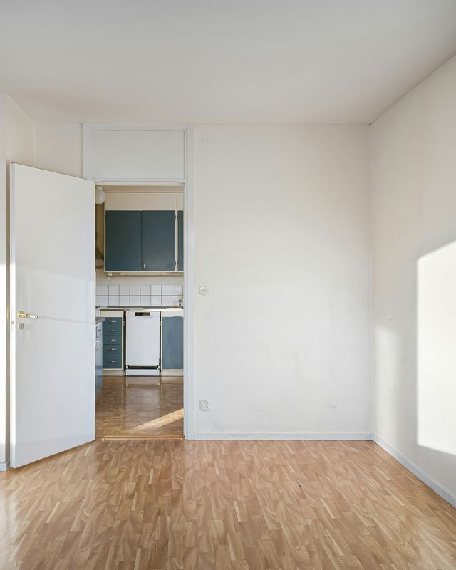 Lege, propere kamer met een parketvloer en zon op de muur